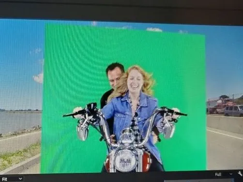 A man and a woman are riding a motorcycle on a green screen.